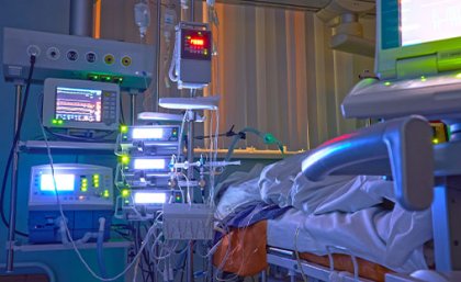 A photo of a hospital bed and medical equipment and monitors beside it. 